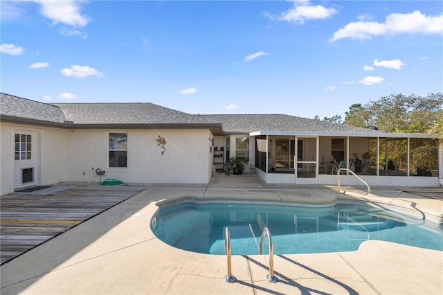 pool with a patio area, a wooden deck, and a sunroom