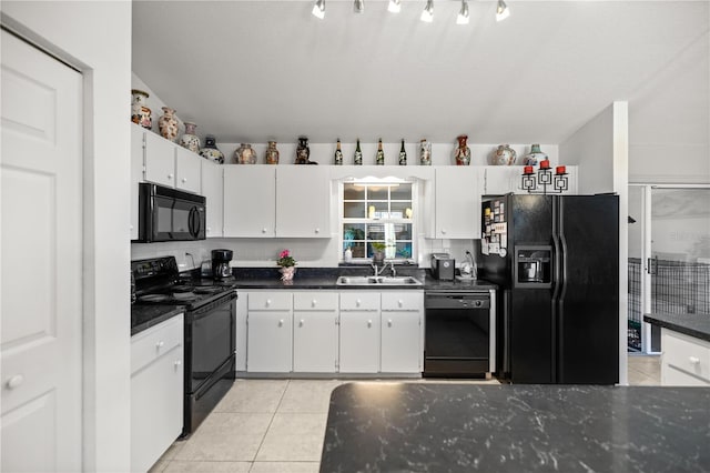 kitchen featuring dark countertops, light tile patterned flooring, white cabinets, black appliances, and a sink