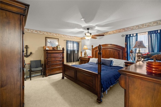 bedroom with light colored carpet, a textured ceiling, a ceiling fan, and multiple windows