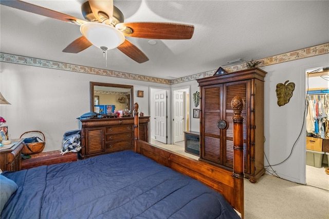 carpeted bedroom featuring ensuite bath and a ceiling fan