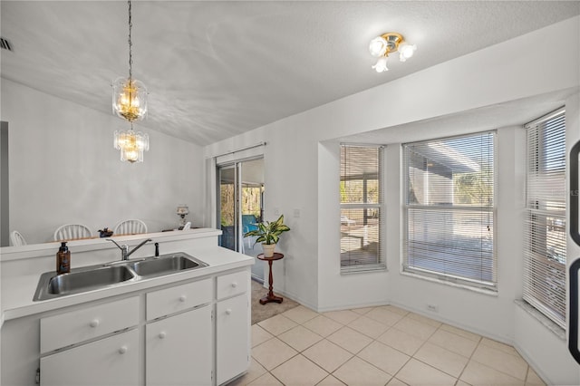 kitchen featuring a sink, decorative light fixtures, white cabinets, light countertops, and light tile patterned floors