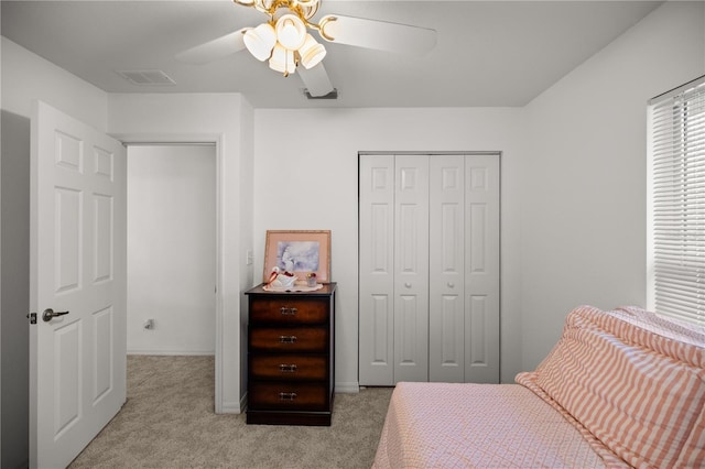 carpeted bedroom with a closet, visible vents, and ceiling fan