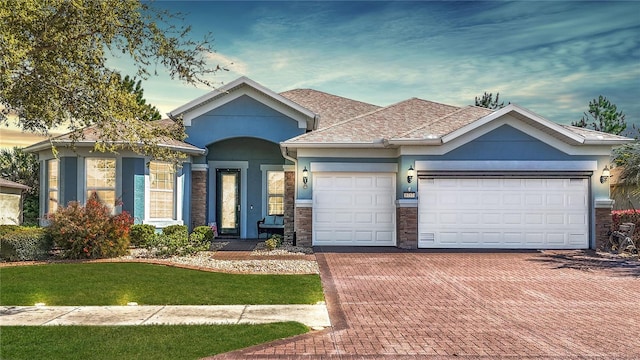 view of front of home with stone siding, stucco siding, decorative driveway, and an attached garage