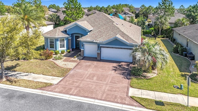 view of front of home featuring decorative driveway, a front lawn, an attached garage, and a shingled roof