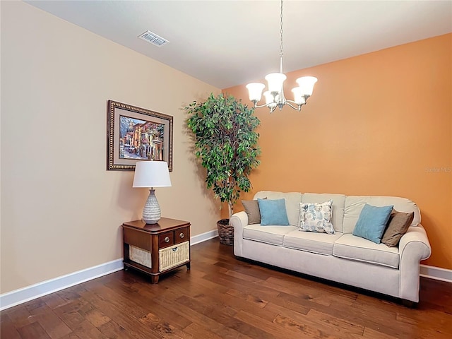 living room featuring a notable chandelier, wood finished floors, visible vents, and baseboards