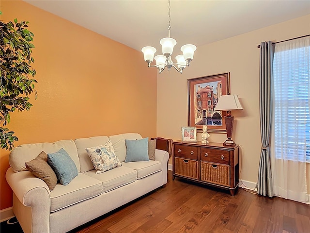 living area with baseboards, a notable chandelier, and wood finished floors