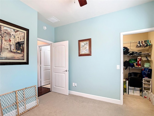 bedroom featuring baseboards, a walk in closet, light carpet, and a closet