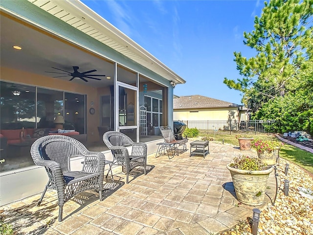 view of patio featuring fence, a ceiling fan, and a sunroom