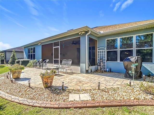 back of house featuring stucco siding, a sunroom, a shingled roof, and a patio area