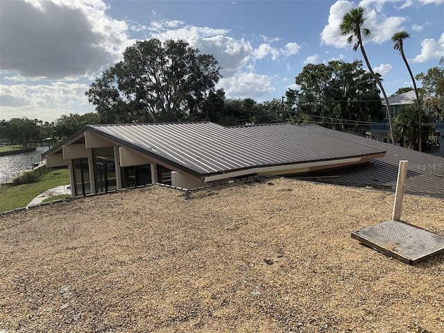 view of side of home with metal roof and a sunroom