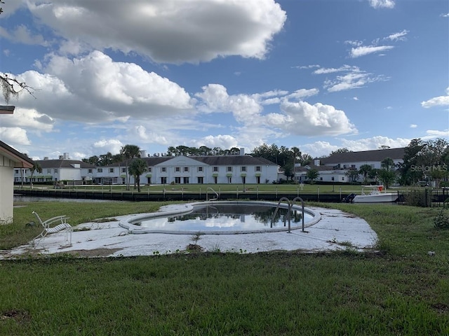 view of swimming pool with a residential view, a lawn, and fence