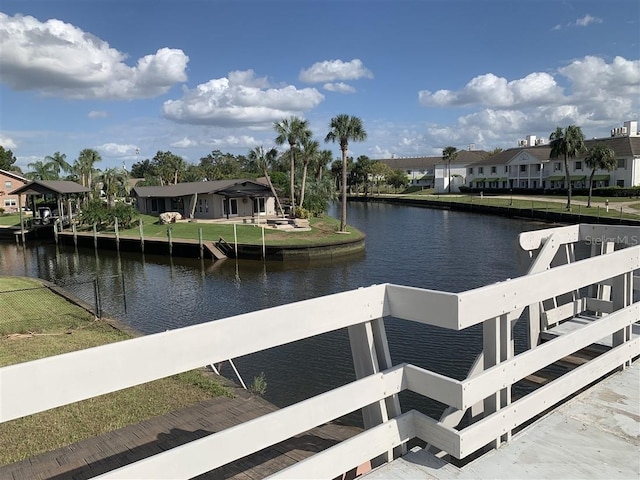 dock area with a residential view, a lawn, and a water view