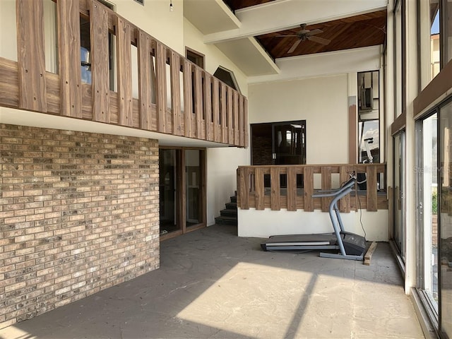 interior space featuring a towering ceiling, brick wall, and a ceiling fan