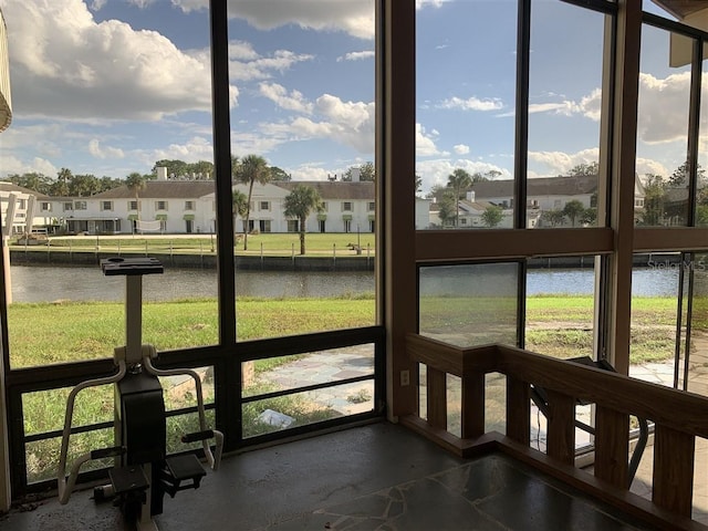 sunroom / solarium featuring a wealth of natural light, a residential view, and a water view