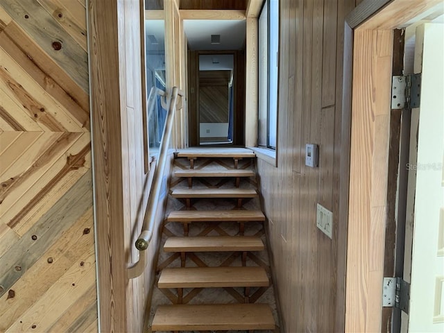 staircase featuring wood walls