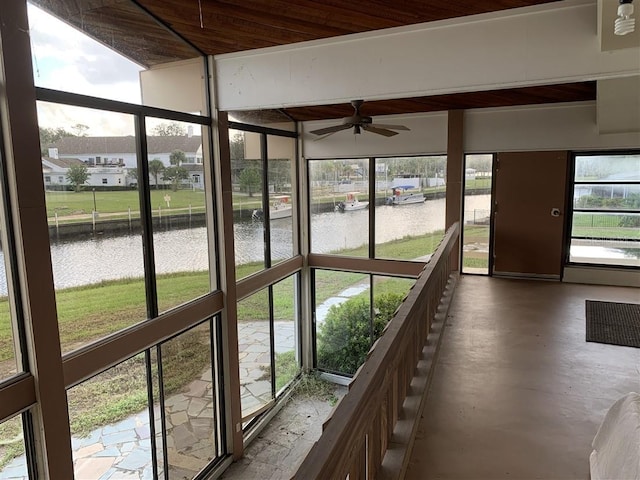 unfurnished sunroom with plenty of natural light, a ceiling fan, and a water view