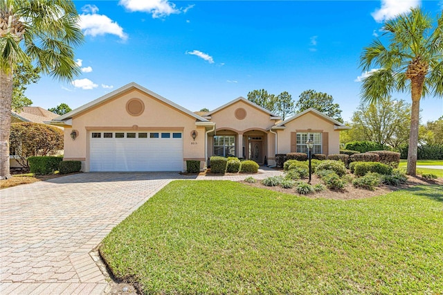 single story home with stucco siding, a front yard, decorative driveway, and a garage