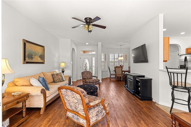 living room with a ceiling fan, arched walkways, dark wood-style flooring, and baseboards