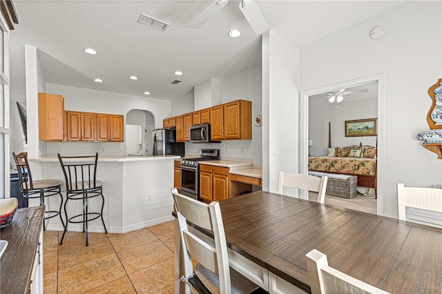 kitchen featuring visible vents, ceiling fan, appliances with stainless steel finishes, a peninsula, and arched walkways