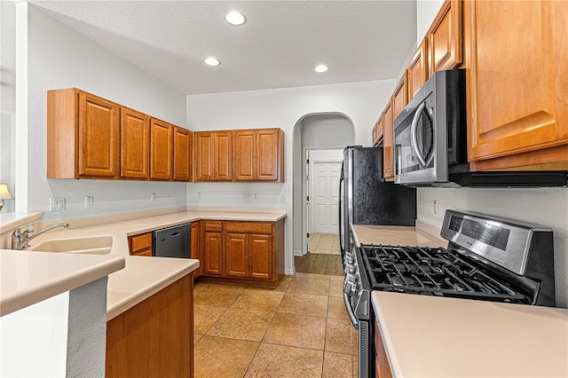 kitchen with recessed lighting, a sink, light countertops, appliances with stainless steel finishes, and brown cabinets