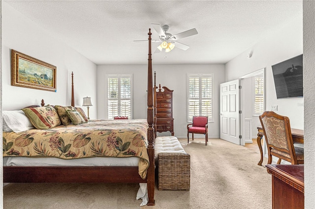 bedroom with a textured ceiling, multiple windows, a ceiling fan, and light carpet