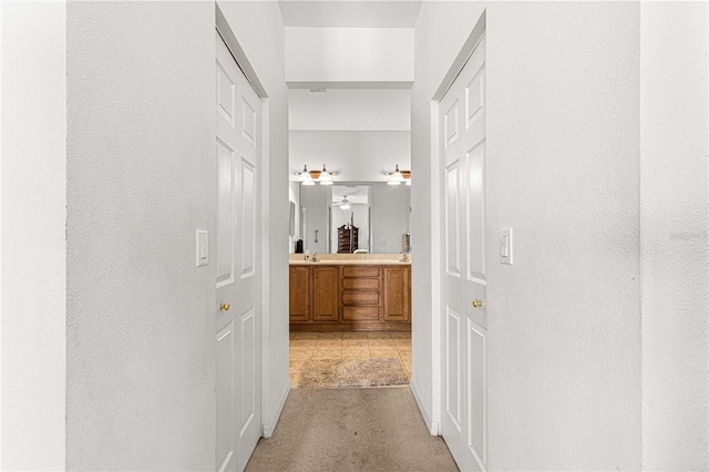 corridor featuring a sink and light carpet