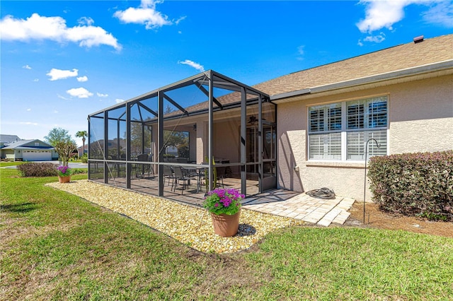 rear view of property featuring a patio area, stucco siding, a lanai, and a yard