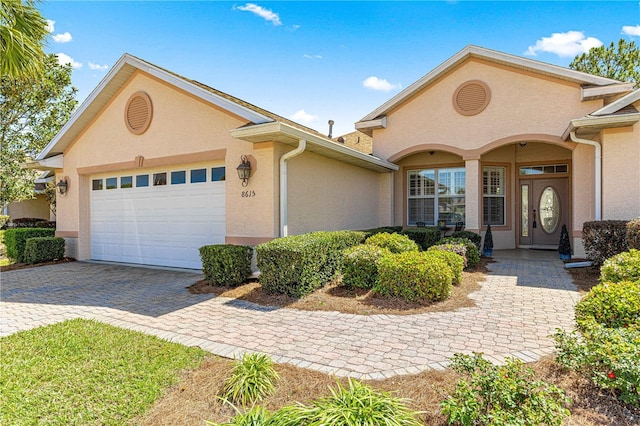 view of front of property featuring decorative driveway, a garage, and stucco siding