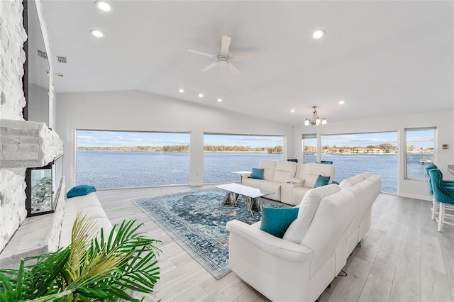 living room with light wood finished floors, lofted ceiling, a fireplace, and a water view