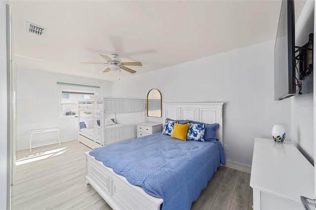 bedroom featuring light wood-style flooring, baseboards, visible vents, and ceiling fan