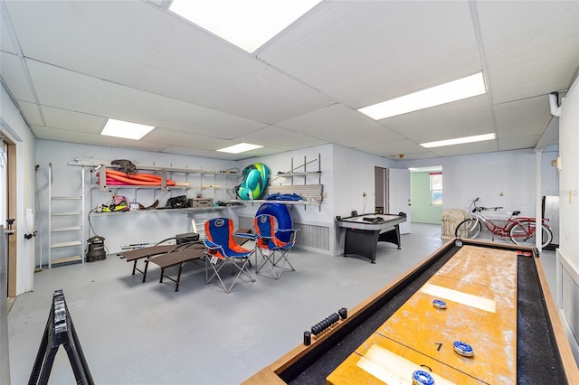 game room with a paneled ceiling and finished concrete floors