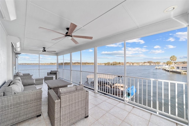 sunroom with a ceiling fan and a water view