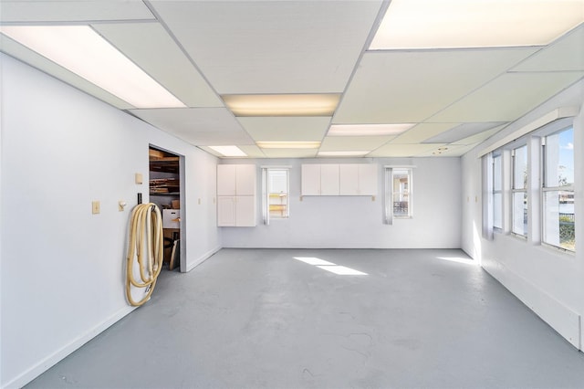 empty room featuring a drop ceiling, concrete floors, and baseboards