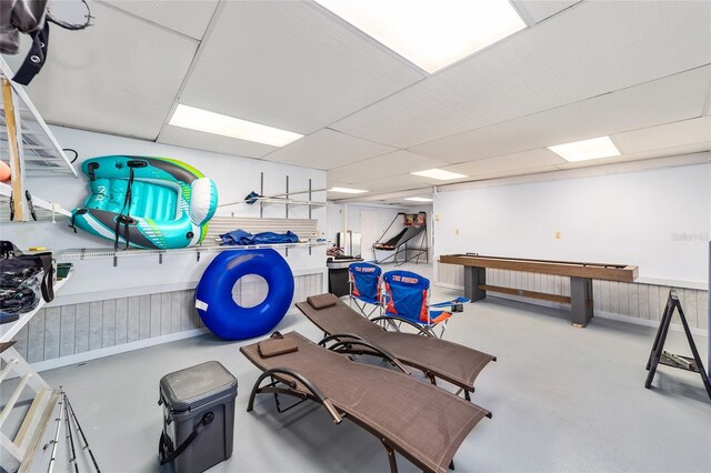 miscellaneous room with finished concrete flooring and a wainscoted wall