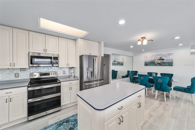 kitchen featuring a kitchen island, recessed lighting, stainless steel appliances, decorative backsplash, and light wood-style floors