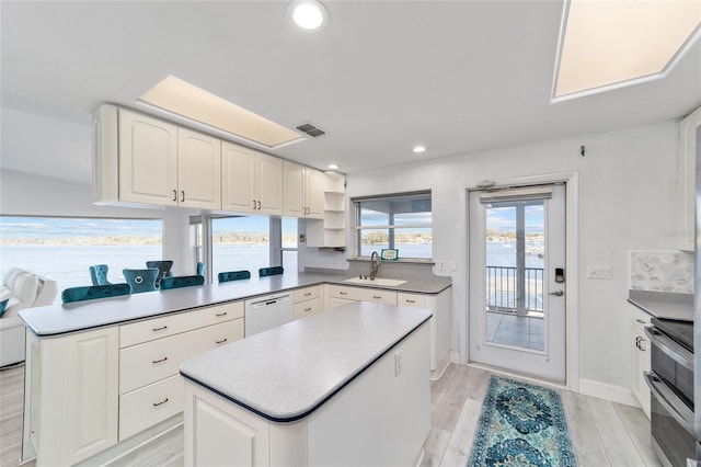 kitchen with visible vents, double oven range, light wood-style flooring, white dishwasher, and a sink