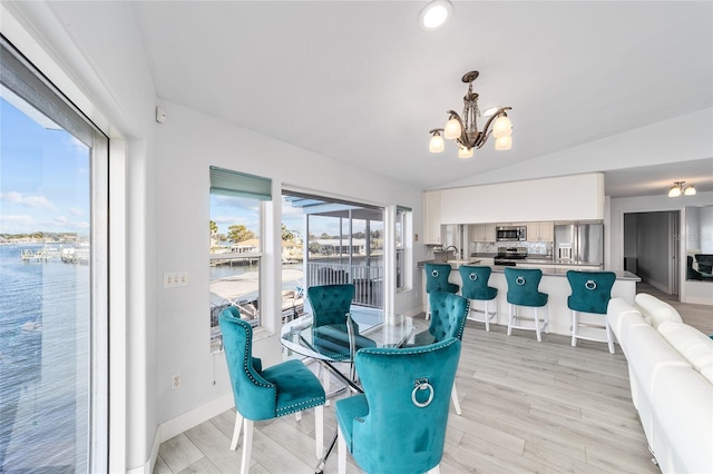 dining area featuring baseboards, lofted ceiling, a chandelier, and light wood finished floors