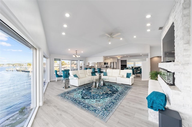 living area with light wood finished floors, plenty of natural light, ceiling fan with notable chandelier, and visible vents