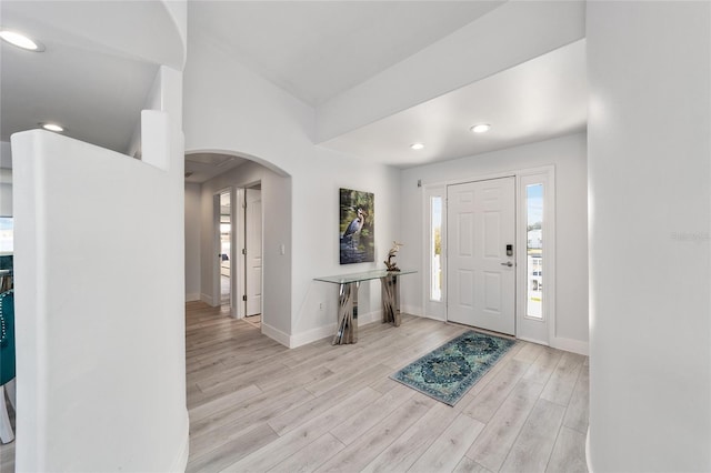 entryway featuring recessed lighting, light wood-type flooring, arched walkways, and baseboards