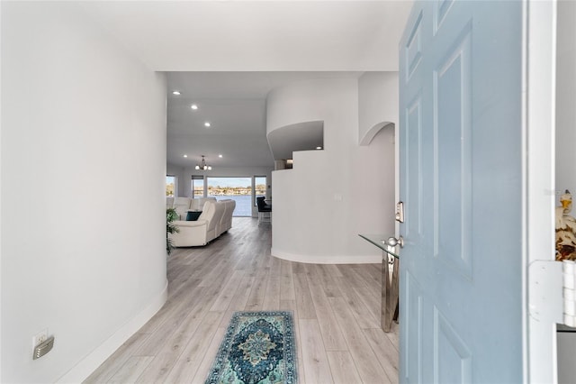 entryway featuring light wood-style flooring, recessed lighting, baseboards, and arched walkways