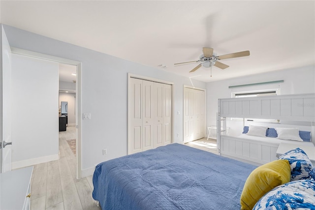 bedroom with baseboards, a ceiling fan, light wood-style floors, and multiple closets