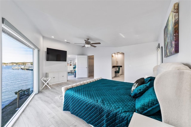 bedroom featuring a spacious closet, access to exterior, light wood-style flooring, arched walkways, and a ceiling fan