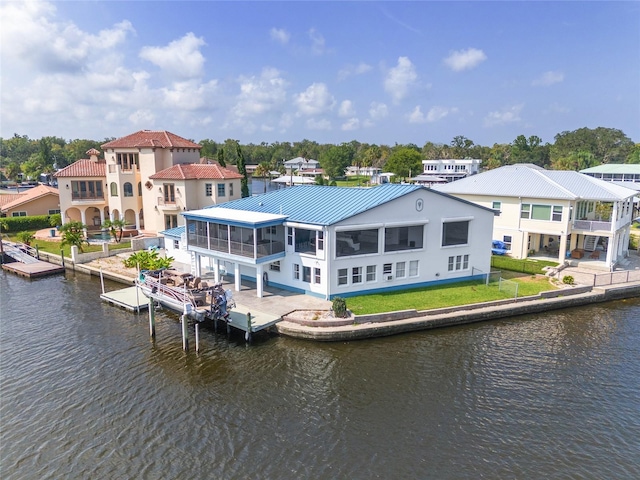 back of house with metal roof, a residential view, a water view, and a sunroom