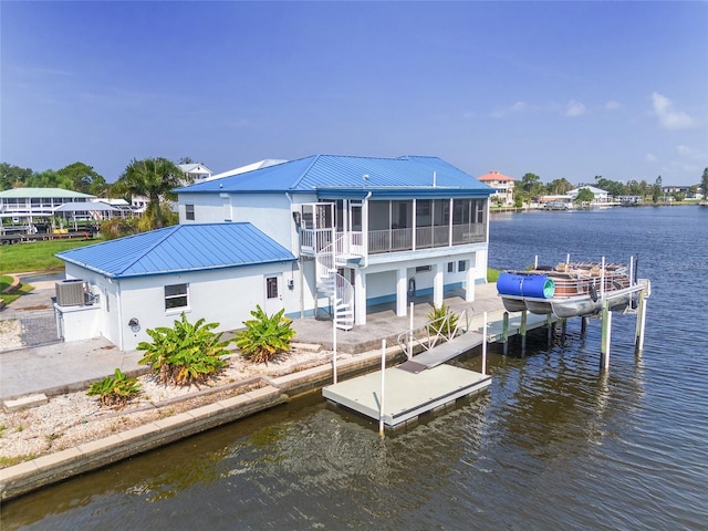 view of dock with cooling unit, a water view, stairs, and a patio area