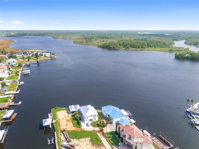 drone / aerial view featuring a view of trees, a water view, and a residential view