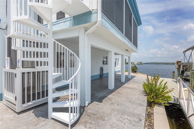 view of patio / terrace with a dock, stairway, and a water view