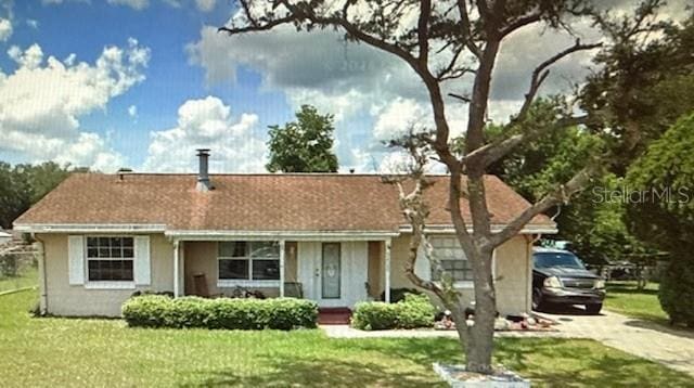 single story home featuring stucco siding, a front lawn, and driveway