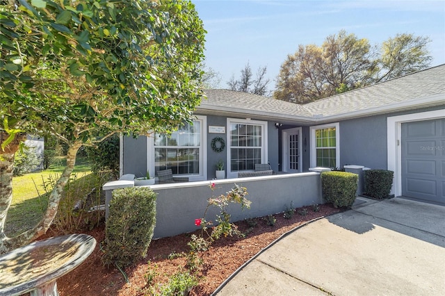 view of front of home with stucco siding, an attached garage, and a shingled roof