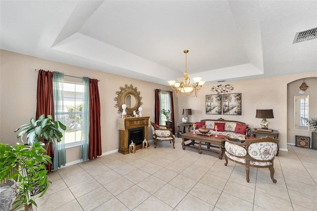 living area with visible vents, baseboards, a tray ceiling, light tile patterned flooring, and a notable chandelier