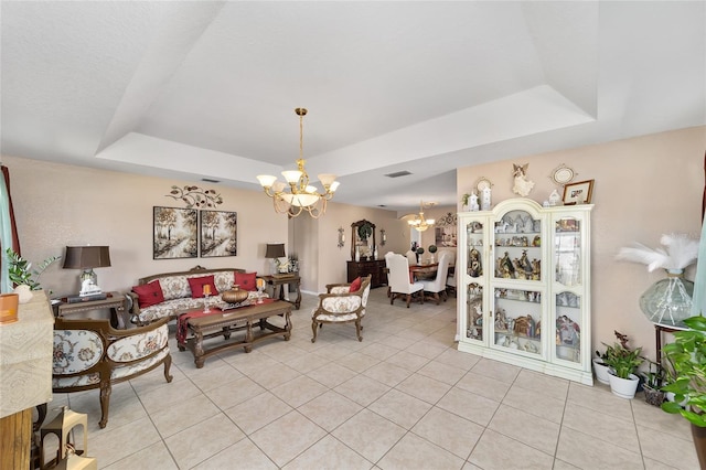 living area featuring a raised ceiling, light tile patterned floors, visible vents, and a chandelier